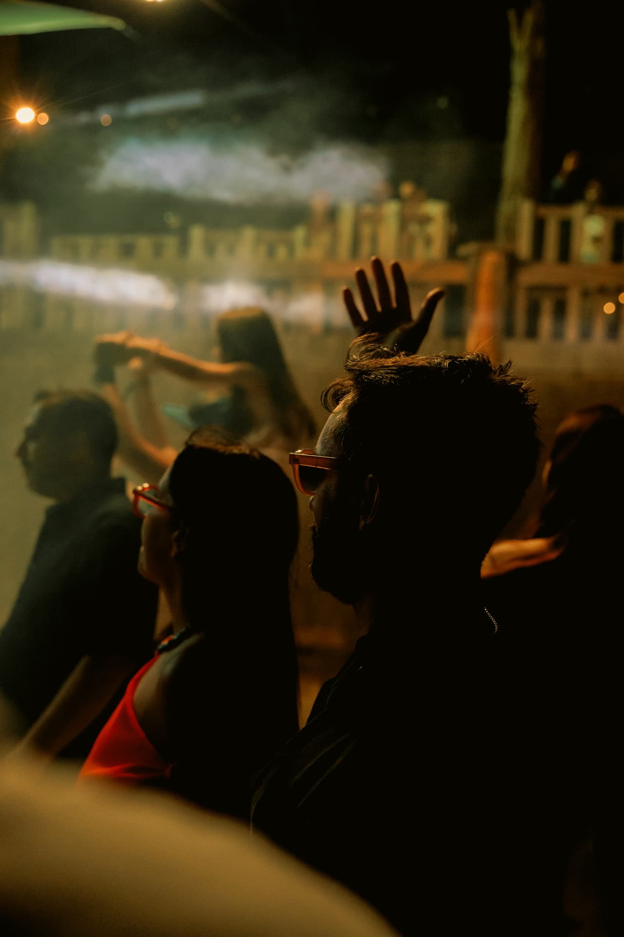 Hands raised through the smoke at night